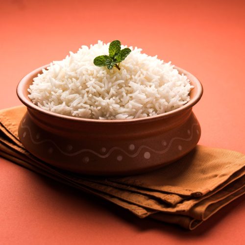 Cooked plain white basmati rice in terracotta bowl over plain or wooden background